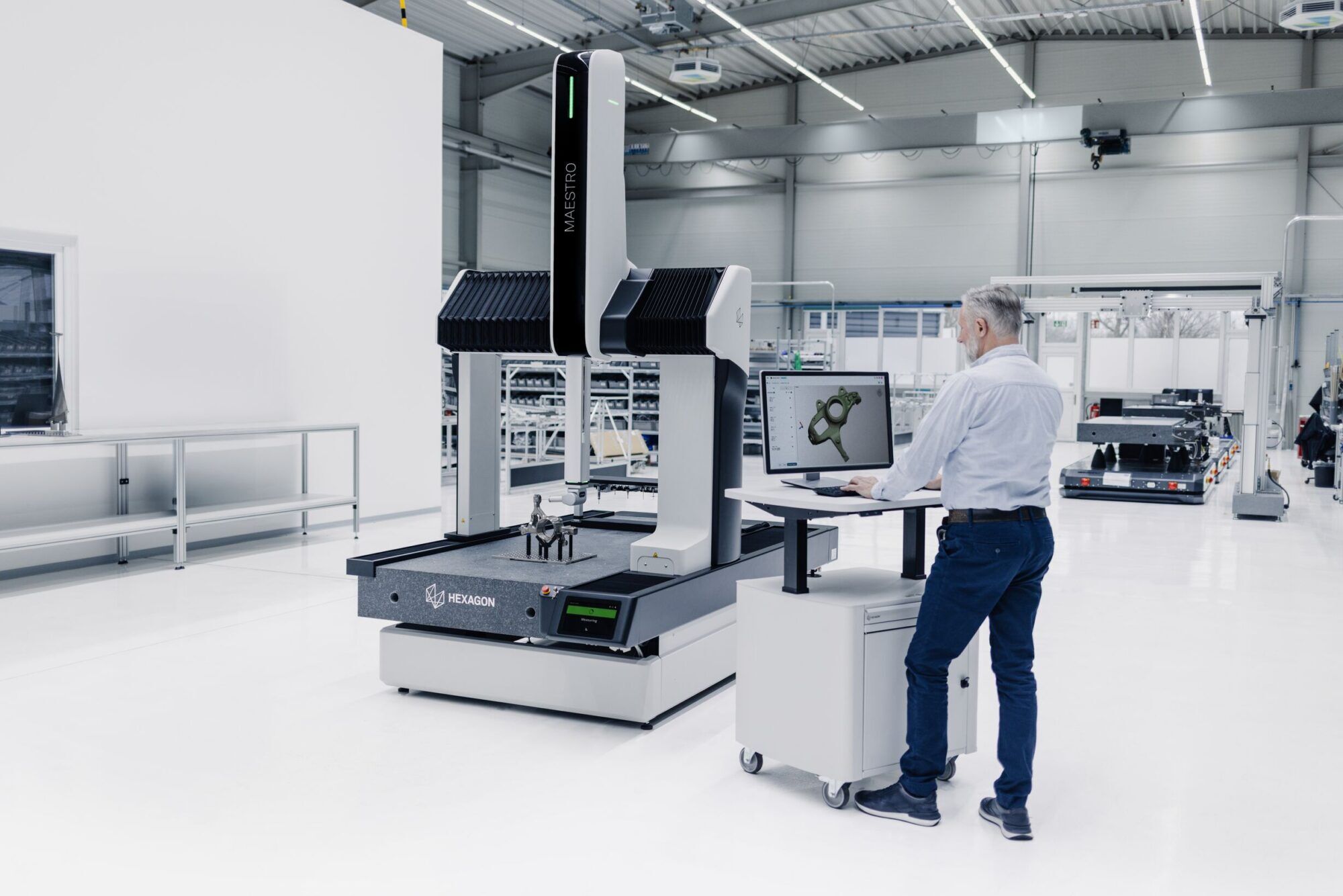 Máquina de medición por coordenadas Hexagon MAESTRO con un operario y un componente sobre la mesa de medición